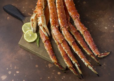 Lezzetli taze limon dilimleri ve biberiye, kahverengi zemin ahşap tahta üzerinde Kamçatka yengecin pençe Kral