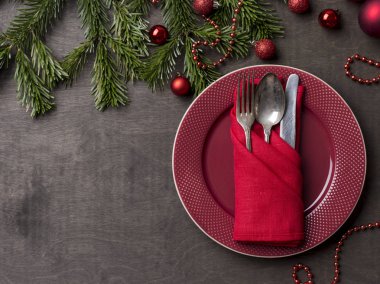 Noel ve yeni yıl kırmızı tabak, çatal, kaşık ve bıçak ile Noel ağacı dalı ve Noel oyuncaklar ahşap arka plan, kırmızı peçeteye hizmet veren. Tatil yemek. Tablo kümesi. Dekorasyon öğesi ve kopya alanı