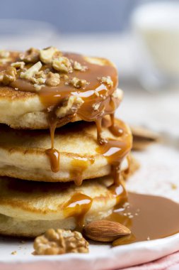 Makro haşlanmış yoğunlaştırılmış süt, karamel ve açık renkli, beyaz plaka üzerinde fındık ile lezzetli krep yığını. Romantik tatlı arka plan