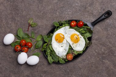 Sahanda yumurta, domates ve taze yeşil, roka, ıspanak, kahverengi zemin malzemelerle ile kavram arka plan. Sağlıklı yaşam kavramı
