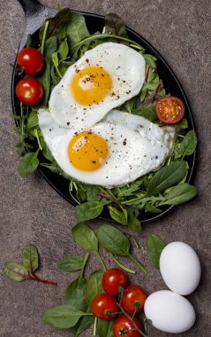Taze ot ve kiraz domates, pan kahverengi zemin günü kahvaltıda kızarmış yumurta. Lezzetli ve sağlıklı yaşam biçimi kavramı