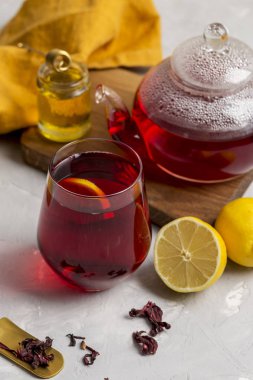 Limonlu, cam Çaydanlık, hibiscus çay (pembe, Agua de flor de Jamaica) şeffaflık bardak tatlım tatlım sopa ve turuncu peçete, ışık arka plan ile. Taze çay saati kompozisyon. Sağlıklı yaşam kavramı