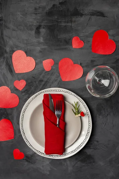 Holiday and romantic serving plate with fork, knife, napkin, strawberry and red heart shaped cards at black background. Top view, close up