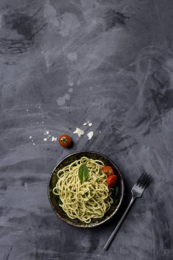 Makarna ile pesto, cherry domates, siyah arka plan, çatal ile kase parmesan peynir. Yatay üstten görünüm. Sağlıklı gıda kavramı