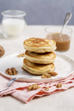 Amerikan krep ile yoğunlaştırılmış süt, çatal ve pembe peçete ile beyaz tabak fıstık. Sağlıklı gıda kavramı