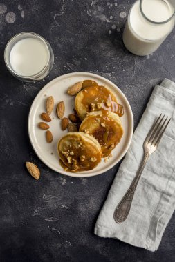 Karamel ve beyaz tabak, çatal, peçete, fındık ile Amerikan krep kavanoz karamel ve siyah arka plan, süt ile. Sağlıklı Kahvaltı, üstten görünüm kavramı