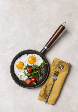Siyah pan kızarmış yumurta, taze otlar ve kiraz domates, çatal ve peçete, beyaz arka plan ile. Sağlıklı gıda kavramı. Üstten Görünüm, boş alan