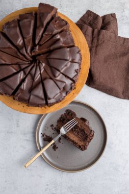 Bütün pastayı ahşap tepsi ile gri plaka çikolatalı pasta dilimi