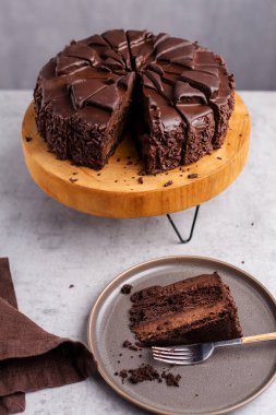 Ahşap stand tüm çikolatalı pasta dilimi gri plaka üzerinde