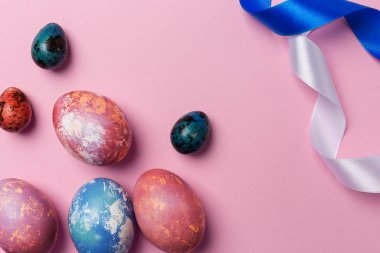 Pembe bir arka plan üzerinde beyaz ve mavi kurdele ile tatil Paskalya yumurtaları