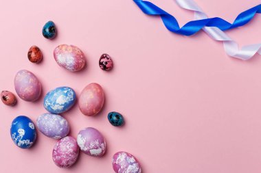 Pembe bir arka plan üzerinde beyaz ve mavi kurdele ile Paskalya yumurtaları