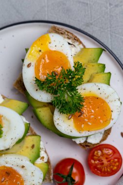 Haşlanmış yumurta ile tahıl ekmek arası sandviç ve avokado plaka üzerinde kapatın