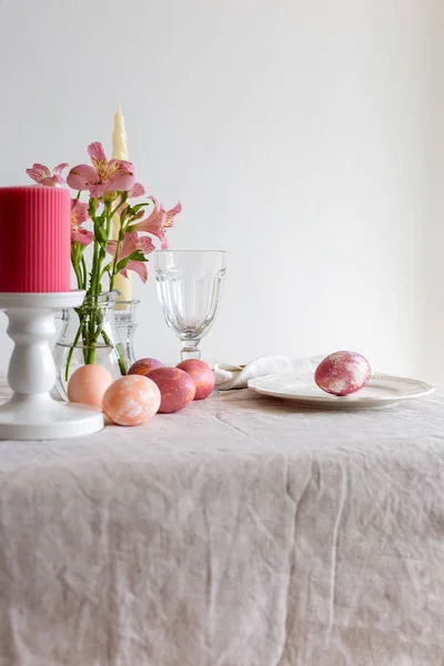 Easter table set on linen tablecloth with Easter egg on plate with decor.