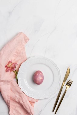 Paskalya servis plakası. Mermer arka planda sofra ve pembe peçete ile beyaz plaka üzerinde Paskalya pembe yumurta