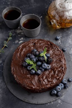 Koyu arka plan üzerinde çaydanlık ve bardak ile Çikolatalı kek