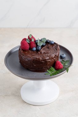 Parlak arka planda gri plaka üzerinde çilek dekor ile çikolatalı kek kapatın