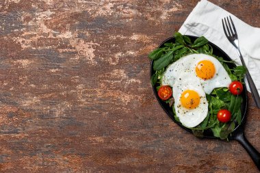 Kahverengi arka planda yumurta ve kiraz domates ile Tava