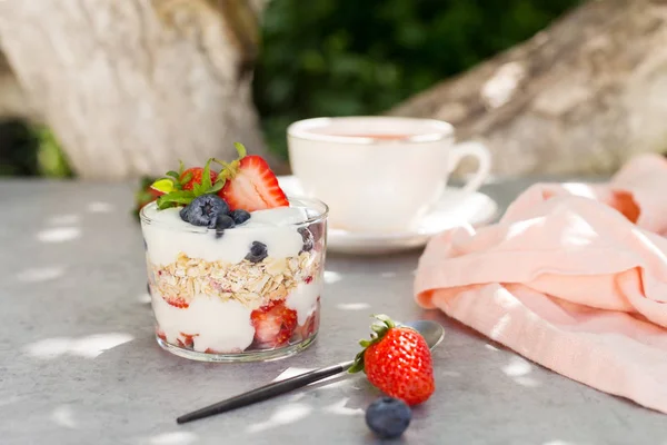 Harina de avena con yogur con fresas y arándanos con cuchara y taza de té —  Fotos de Stock