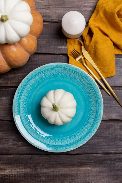 Empty serving plate with pumpkin, tableware and napkin on wood background