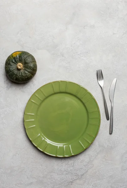 Piatto verde vuoto con stoviglie su cemento verde con zucca verde — Foto Stock