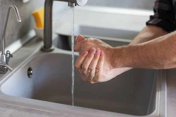 a man washes his hands in the kitchen sink. Modern kitchen
