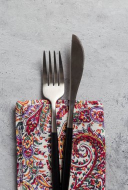 Gümüş takımları gri arka plandaki peçeteye kapatın. Çatal ve bıçak çiçek peçetesinde gri beton arka planda. Asgari tablo kümesi kavramı