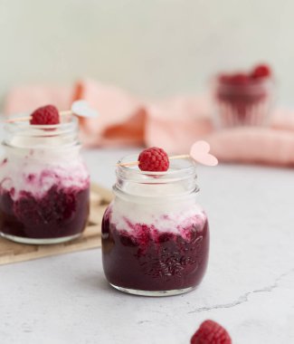 Doğal yoğurt, böğürtlen püresi ve ahududu ile servis edilen sağlıklı bir tatlı.