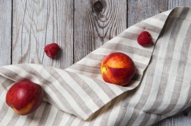 Fresh tasty peaches with raspberry on wooden background. Concept of healthy summer food at wood background with napkin. Top view, flat lay, copy place for text