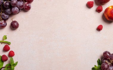 Pembe beton arka planda farklı meyveler içeren çerçeve. Boşluğu üzüm, nektarin, ahududu ve naneyle kopyalayın. Pazar satışı için modern boşluk kavramı