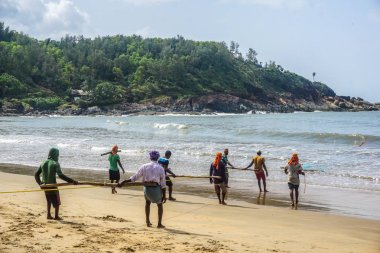 Gokarna Köyü, Karnataka eyalet, Hindistan - 31 Temmuz 2017: Hint erkek uzun bir net kullanarak balık yakalamak. Çok zor olduğu gibi net bir kerede birkaç kişi çekerek vardır.