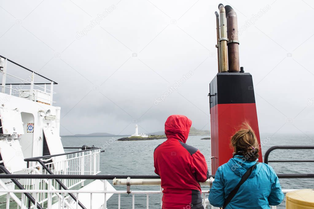 Two tourists looks at the Lighthouse of Lismore during a ferry crossing in the inner Hebrides