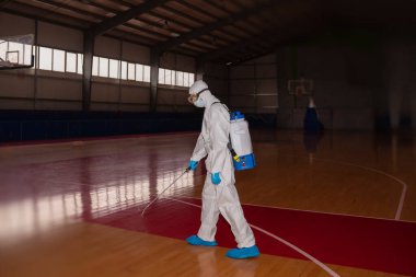 Virüs koruyucu giysiler giyen ve koronavirüs binalarını spreyle dezenfekte eden insanlar.
