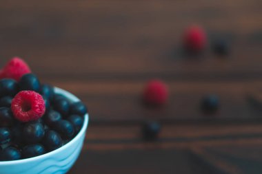 Yaban mersini ve ahududu koyu kahverengi masada kase.