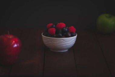 Yaban mersini ve ahududu koyu kahverengi masada kase.