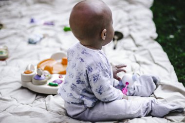 Yaz bahçesinde halıüzerinde oturan küçük bir çocuk