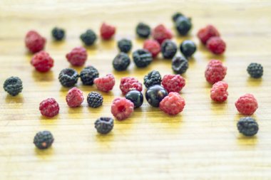 Kırmızı ve siyah ahududu meyveleri ahşap bir Tahta üzerinde dağınık