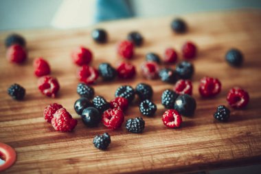 Kırmızı ve siyah ahududu meyveleri ahşap bir Tahta üzerinde dağınık