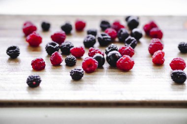 Kırmızı ve siyah ahududu meyveleri ahşap bir Tahta üzerinde dağınık