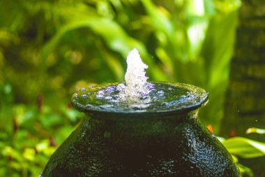 Tropik bir parkta büyük bir sürahi su ile küçük bir çeşme
