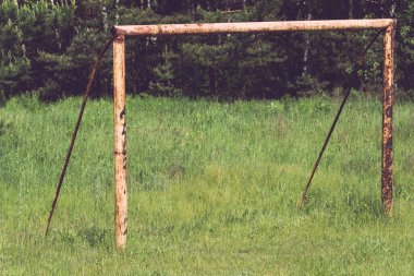 Terk edilmiş bir futbol sahasındaki paslı metal kapılar.