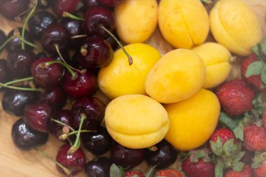 Olgun sulu taze sağlıklı meyve kirazları, kayısılar ve çilekler. 