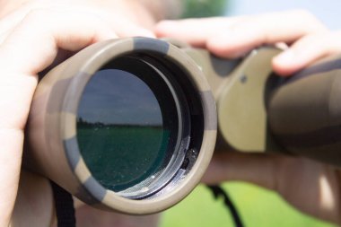 Elinde askeri dürbünü olan genç bir adam.