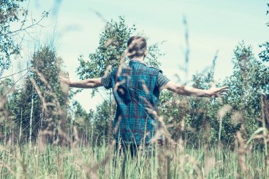 Tarlada kollarını açmış genç bir adam.