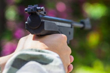 Genç bir tetikçinin elinde büyük siyah bir tabanca.