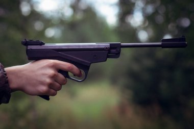 Genç bir tetikçinin elinde büyük siyah bir tabanca.