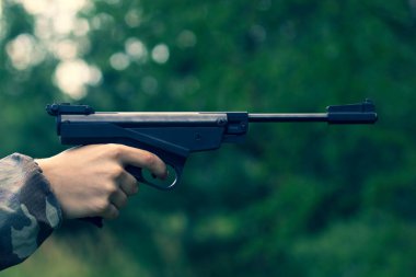 Genç bir tetikçinin elinde büyük siyah bir tabanca.