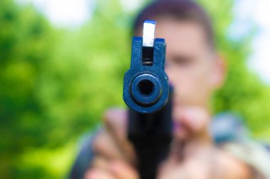 Genç bir tetikçinin elinde büyük siyah bir tabanca.