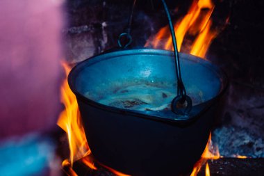 Izgaradaki ateşte, dökme demir bir tencerede sıcak, lezzetli, dumanı üstünde yemek.