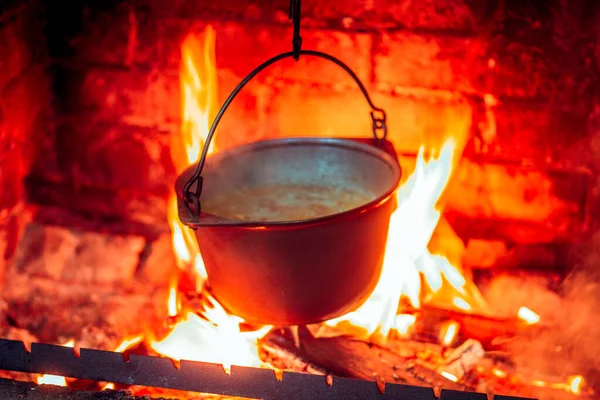 Izgaradaki ateşte, dökme demir bir tencerede sıcak, lezzetli, dumanı üstünde yemek.