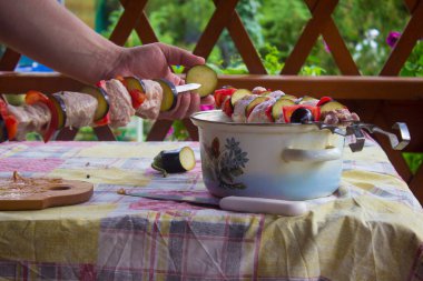 Et, domates ve patlıcan parçaları piknikte bir aşçının ellerinde şişlere dizilmişti.